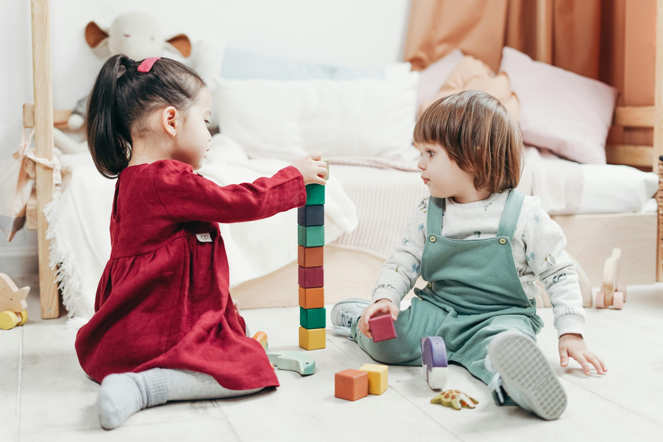 Two children happily playing together with colorful wooden blocks, indoors.
